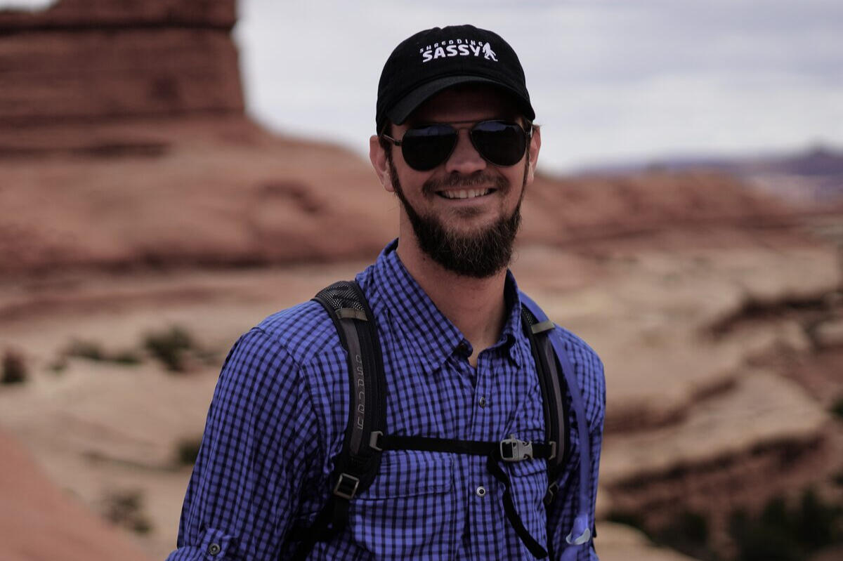 Bearded hiker in a Shredding Sassy cap and gingham shirt in desert light